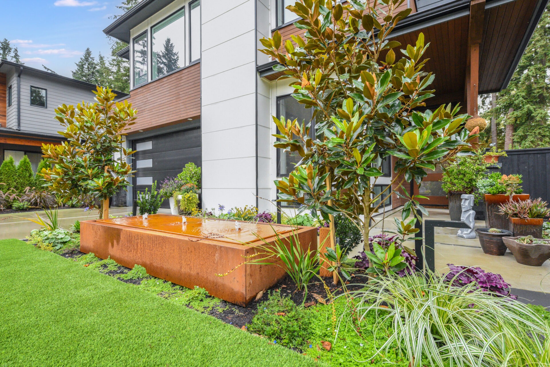 Modern house with a well-manicured garden, featuring lush greenery and a wooden planter. No recognizable landmarks or historical buildings are present.