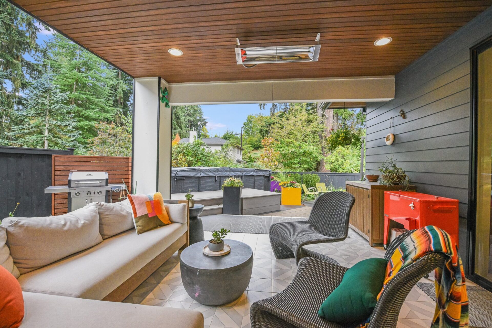 Modern outdoor patio with stylish seating, plants, and a grill. Cozy and inviting space overlooks greenery, perfect for relaxation and entertaining guests.