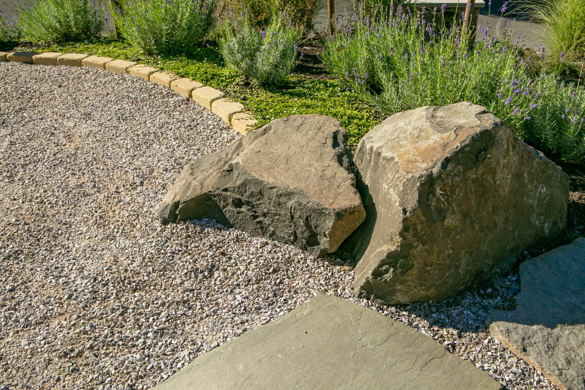 A landscaped garden features large rocks, gravel paths, and lush greenery. The arrangement creates a peaceful, natural atmosphere for outdoor enjoyment.