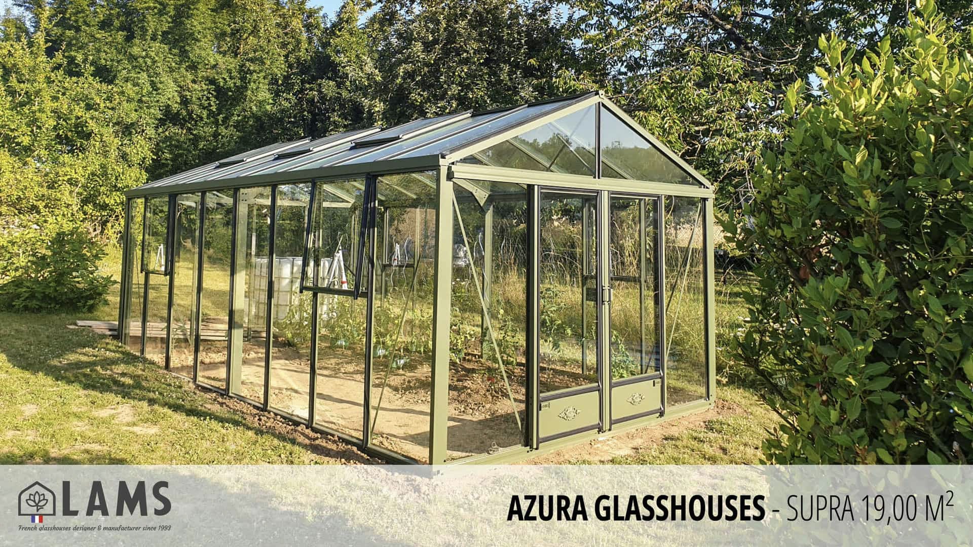 A glasshouse stands in a lush garden setting, surrounded by trees and greenery. The structure is labeled "AZURA GLASSHOUSES - SUPRA 19,00 M²."